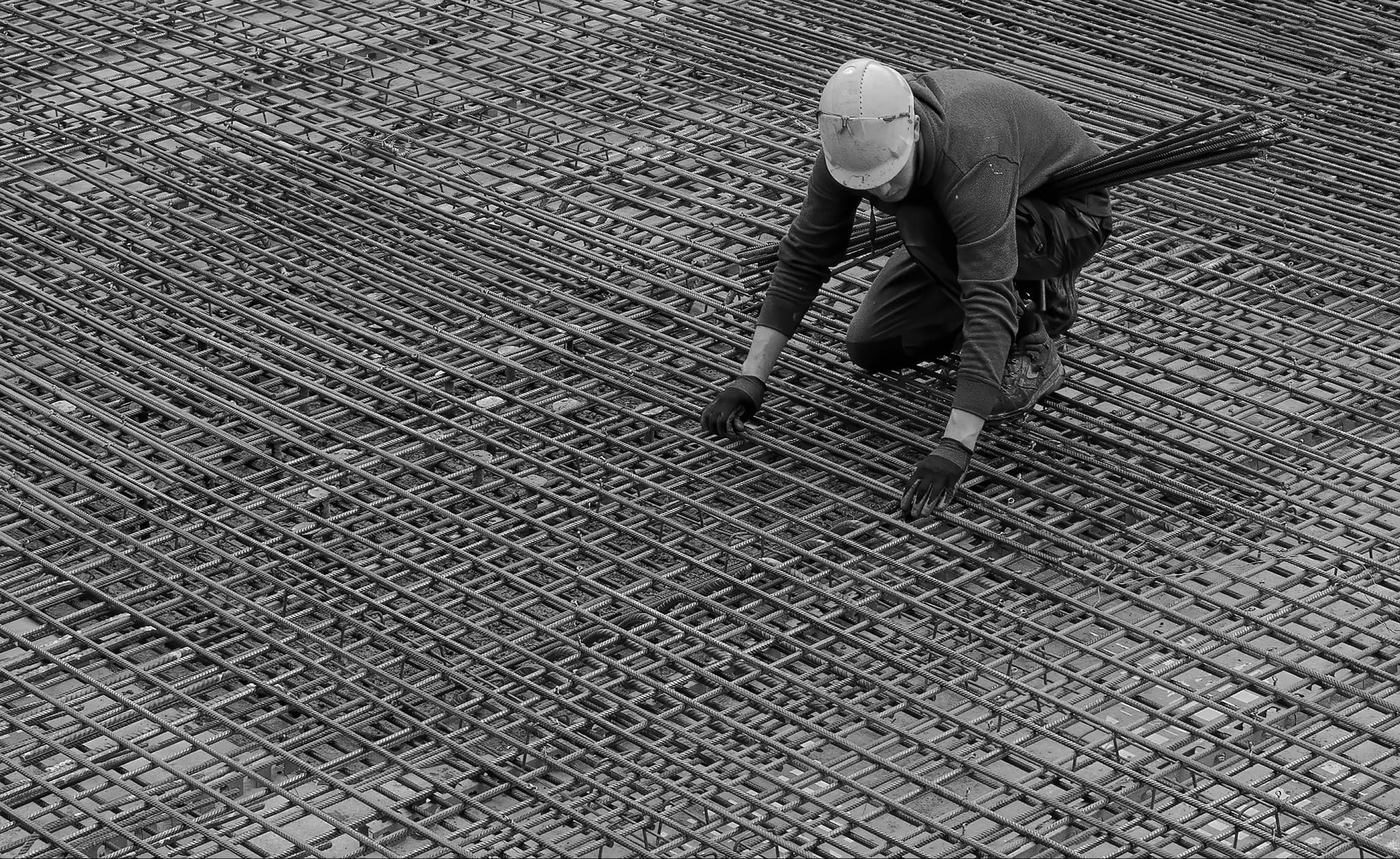 Worker laying rebar mesh on a construction site