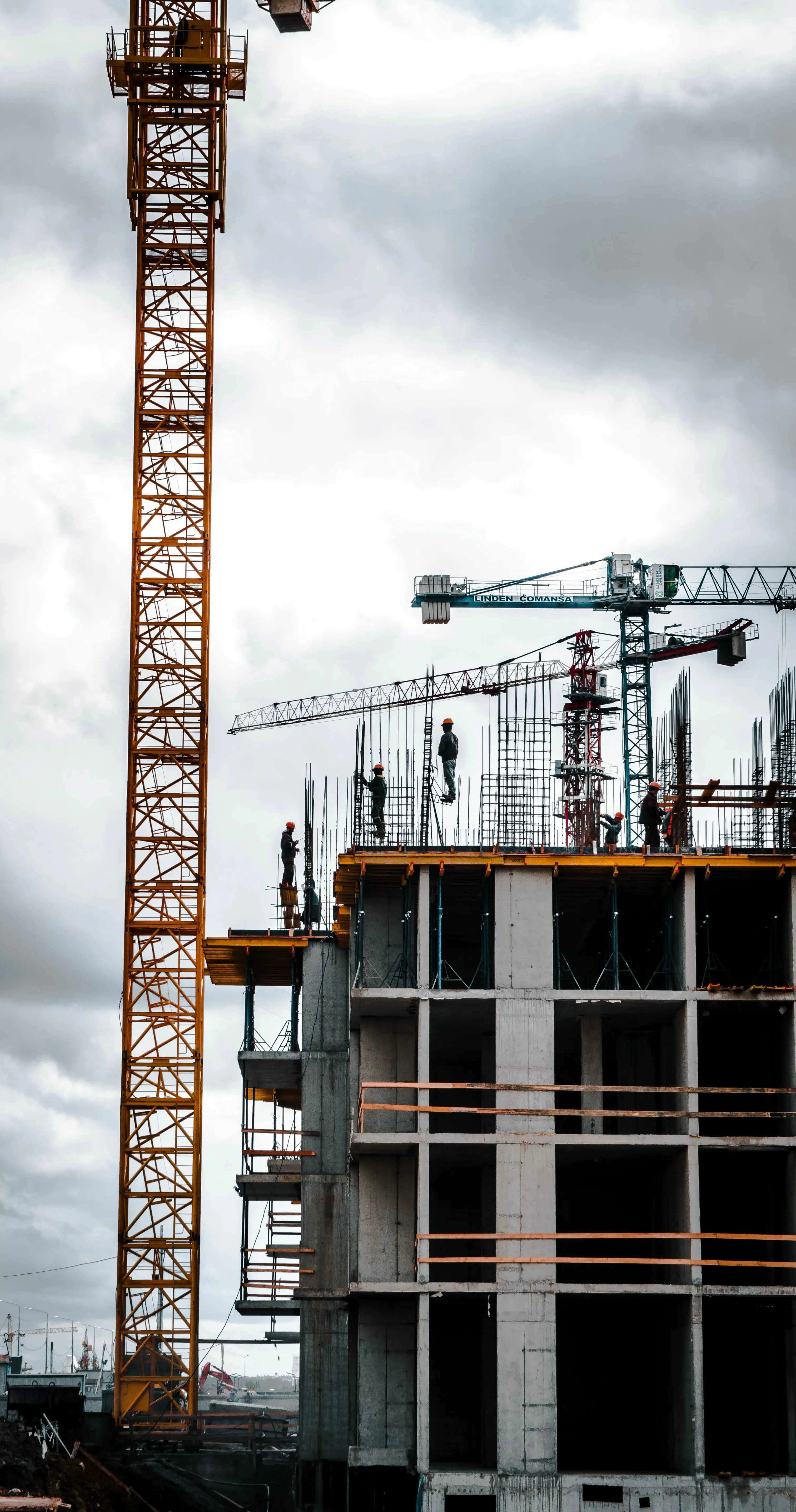 Tower crane and workers on a concrete building under construction